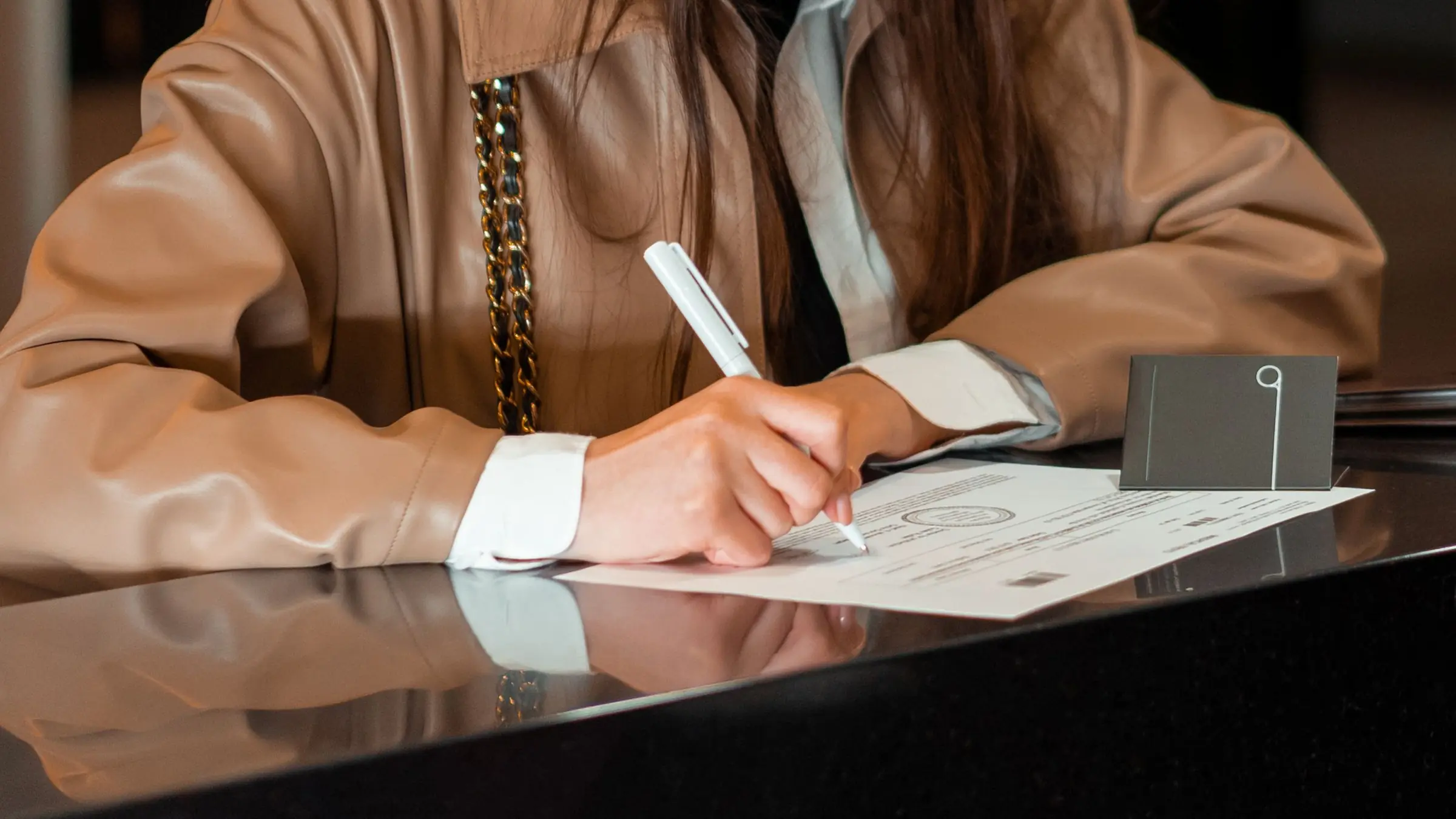 Persona firmando un documento sobre el mostrador de atención de una oficina